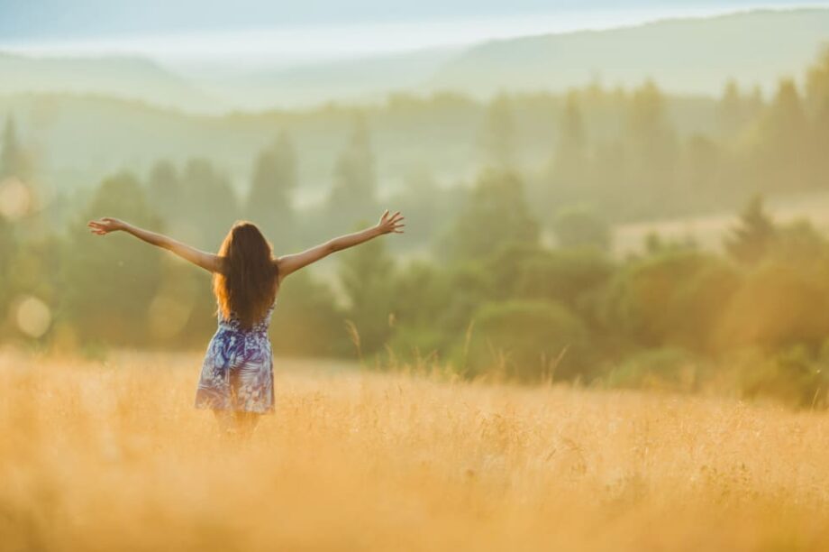 ευτυχία γυναίκα ανοίγει τα χέρια στην εξοχή κάτω από τον ήλιο
